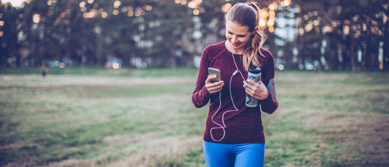 Woman walking in the park listening to music on her smartphone