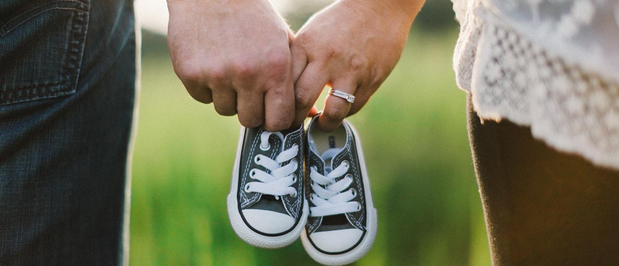 Man and woman holding baby high top sneakers