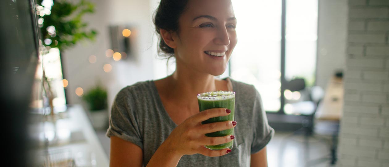 Young woman drinking a green juice