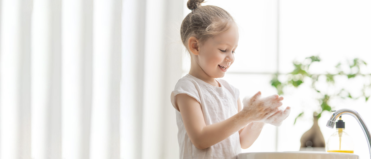 Young girl washing her hands with soap and water at the bathroom sink