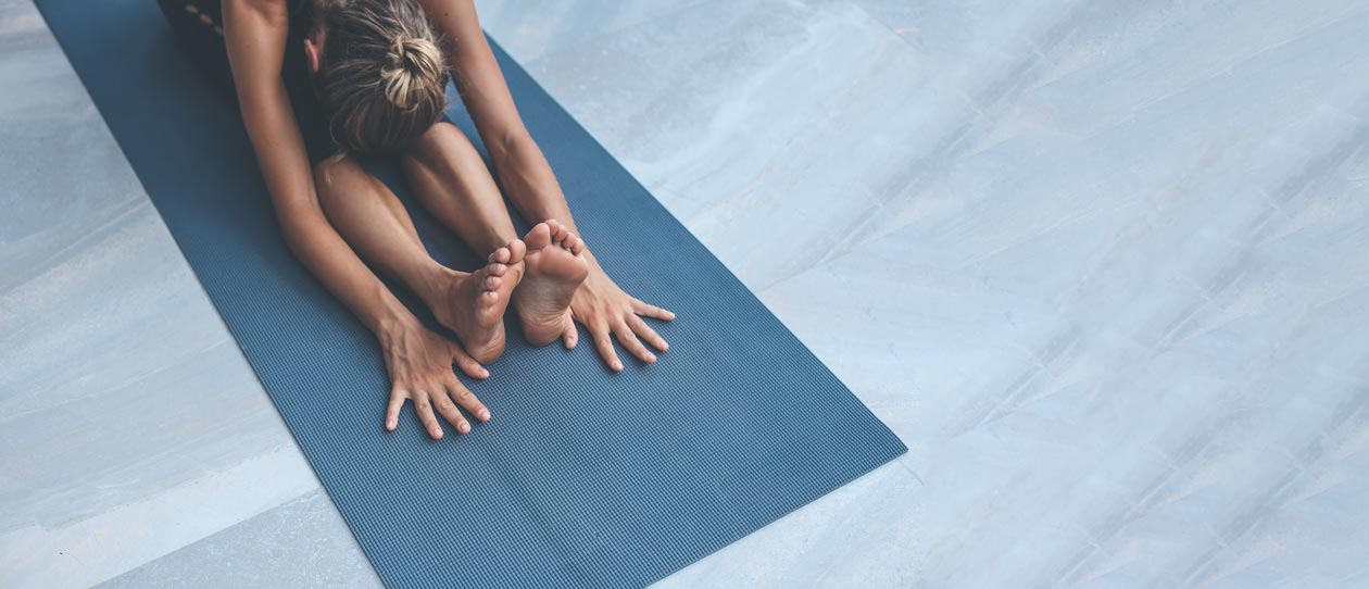 Young woman stretching on a blue yoga mat