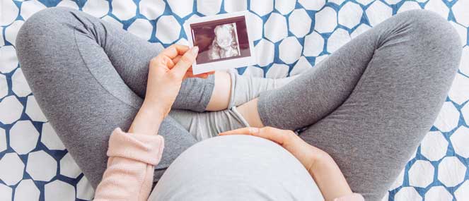 Pregnant women sitting cross-legged looking at ultrasound image