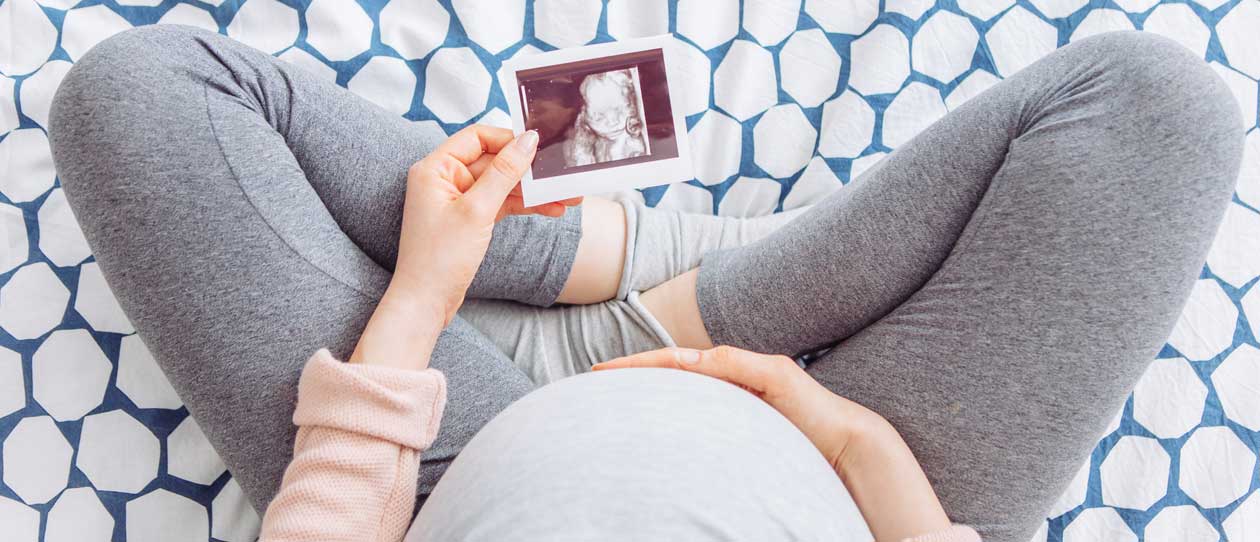 Pregnant women sitting cross-legged looking at ultrasound image