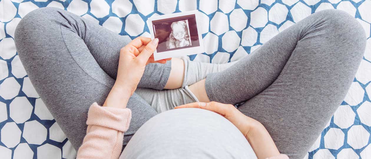 Pregnant women sitting cross-legged looking at ultrasound image