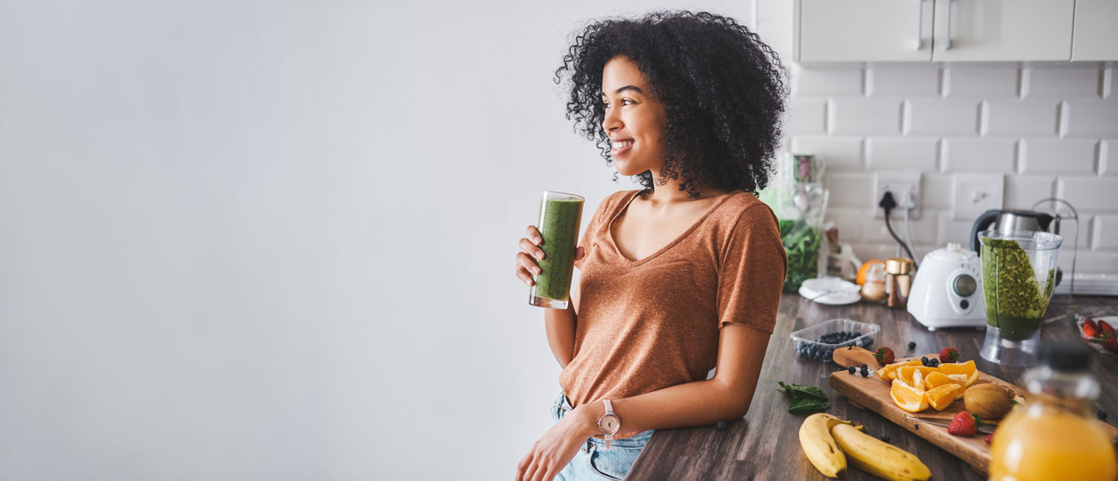 Woman drinking a green smoothie in the kitchen