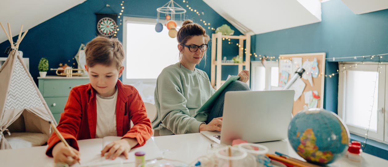 Young boy being home schooled by his mother, while she is working from home