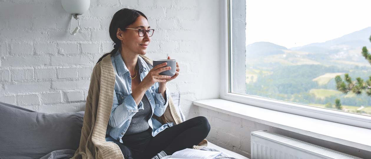 Woman sitting comfortable drinking tea and looking through window